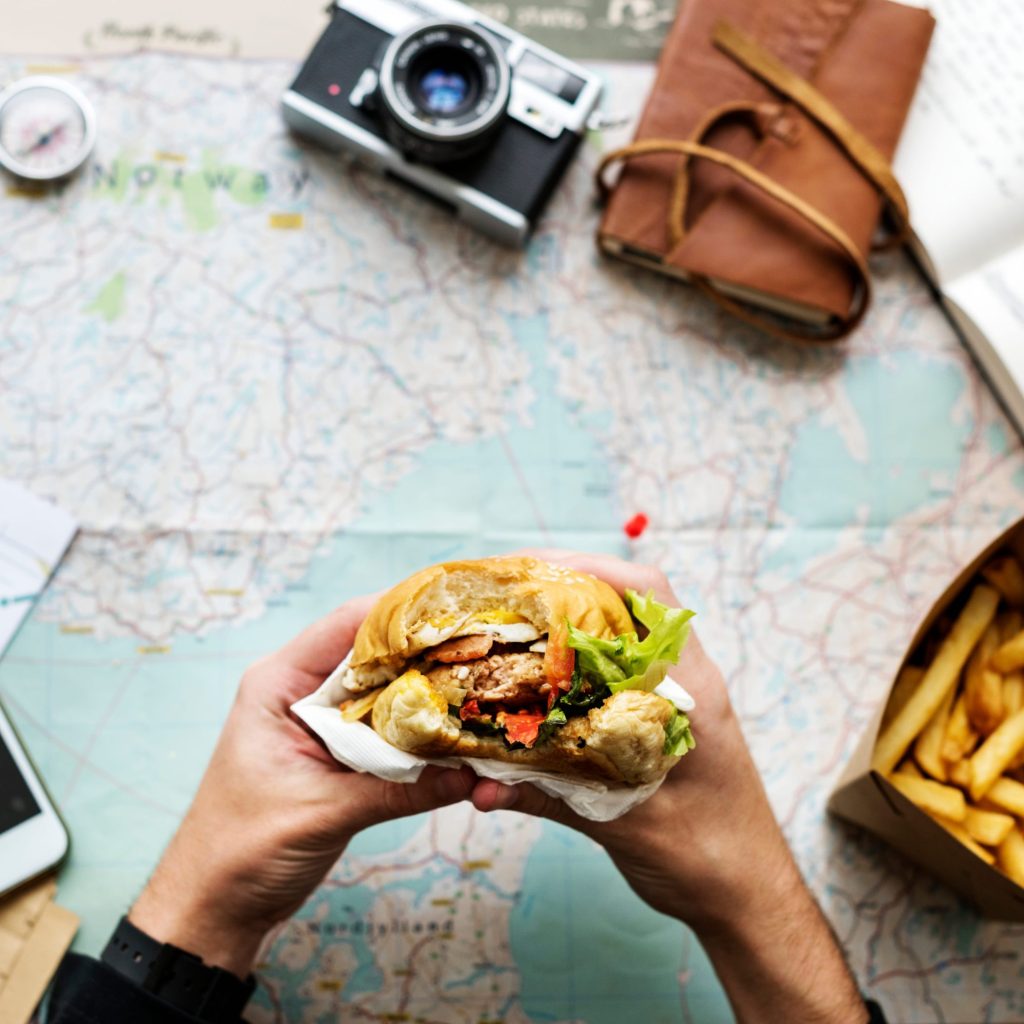 Closeup of hands holding hamburger over map background